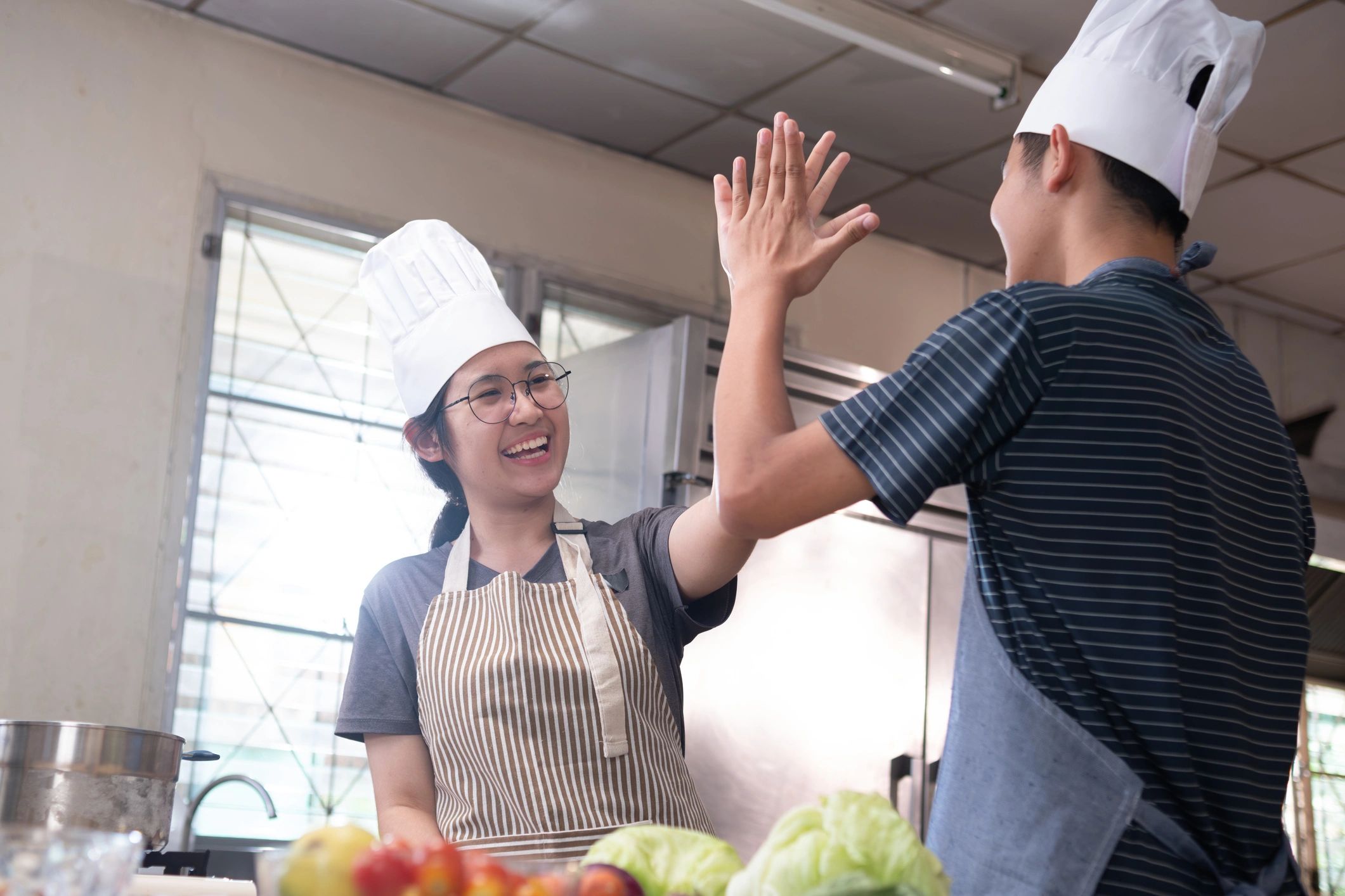 Two chefs celebrating teamwork in a kitchen